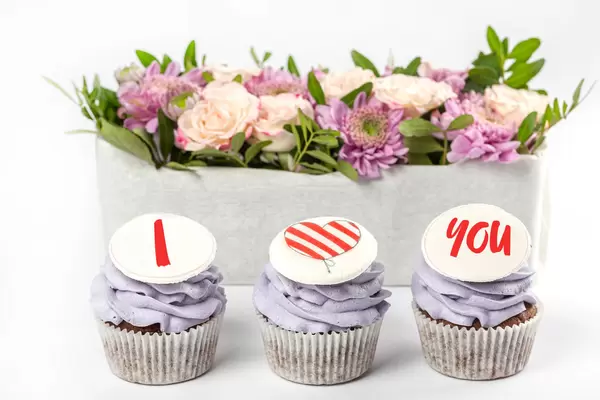 Cupcakes with purple cream and decor i love you on a white background with flowers