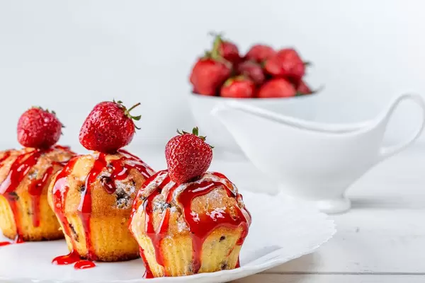 Cupcakes with strawberry sauce and fresh berries on a white plate