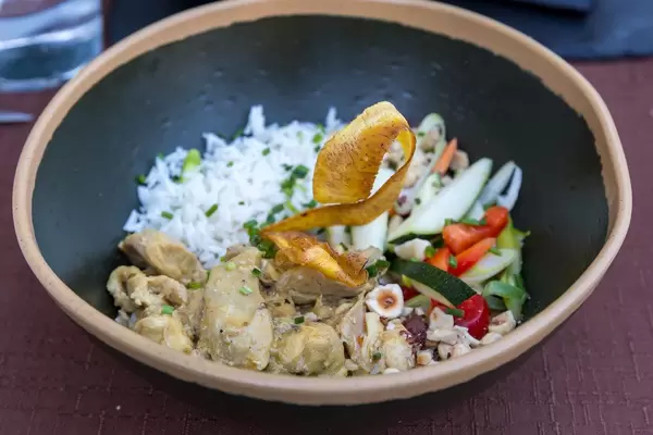 Curry-Landhuhn nach Q11-Art mit Gemüse der Saison und Reis in einem schwarzen Teller bei Q11, Pollença