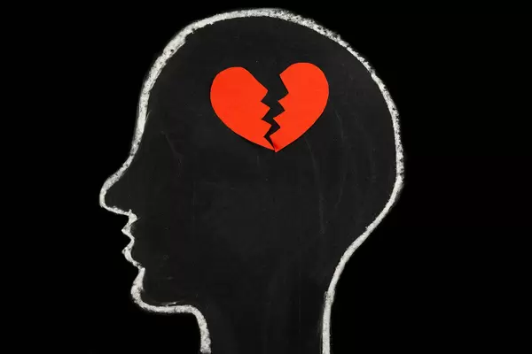 Cut halves of a heart in a silhouette of a human head, the concept of loss, stop loving