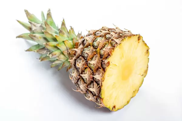 Cut ripe pineapple on white background