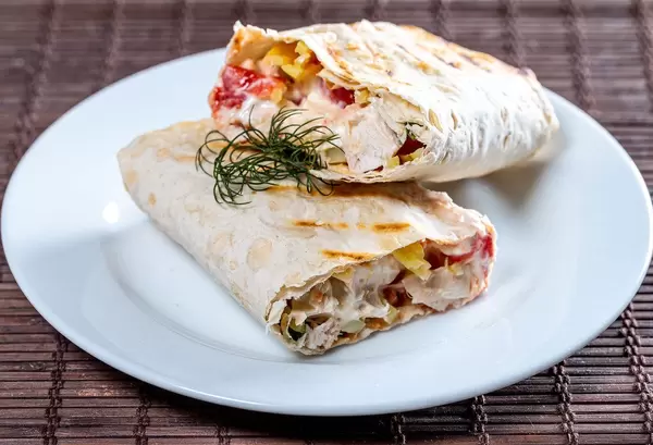 Cut Shawarma with chicken fillet and vegetables on a white plate (Flip 2019)