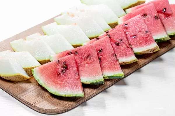 Cut triangular pieces of ripe watermelon and melon on kitchen Board (Flip 2019)