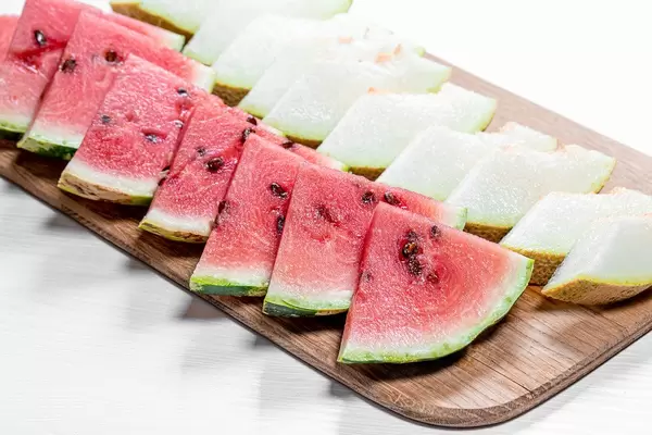 Cut triangular pieces of ripe watermelon and melon on kitchen Board