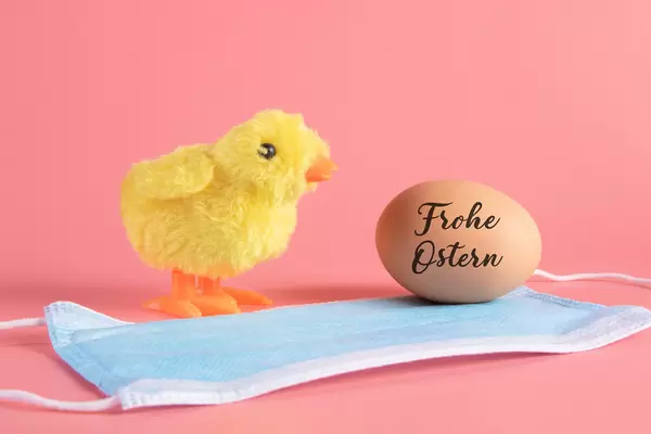 Cute little chicken, medical face mask and egg with Frohe Ostern text