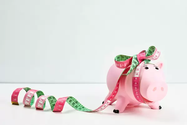 Cute piggy bank wrapped as a gift with measuring tape