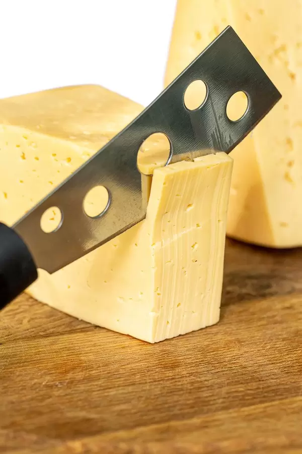 Cutting cheese with a knife, close-up