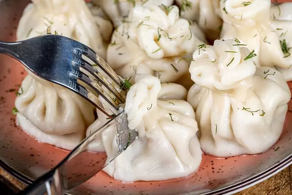 Cutting khinkali with a knife and fork, close-up
