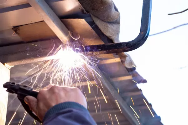 Dachreperaturen werden durch einen Schweißer mit Elektroden durchgeführt