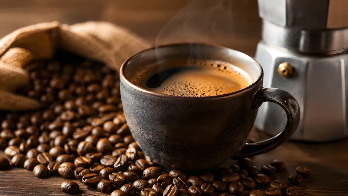 Dampfende Kaffeetasse mit Kaffeebohnen und Mokakanne