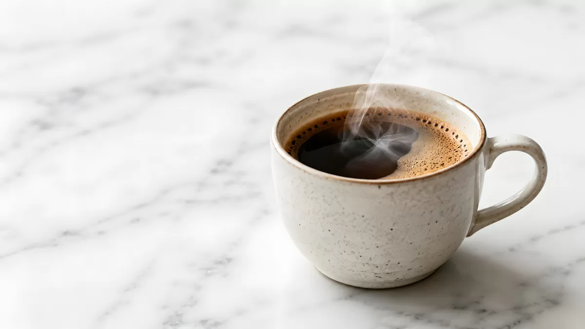 Dampfende schwarze Kaffeetasse auf Marmortisch