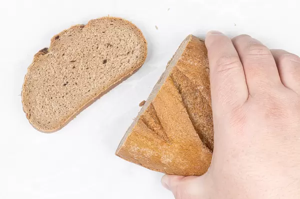 Dark bread with unleavened dough in the hand above table