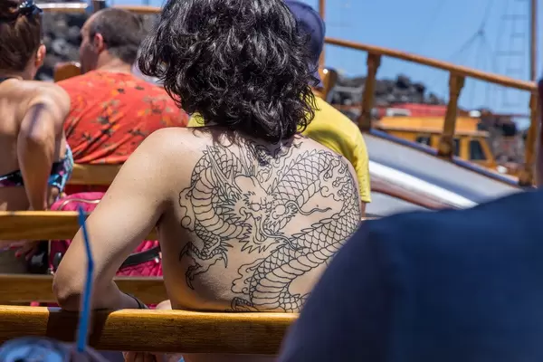 Dark-haired woman with a large dragon tattoo on her naked back