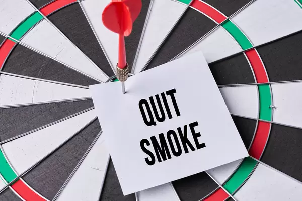 Dart arrow hitting a note on target center of dartboard with text - quit smoke. No smoking, World no tobacco day concept