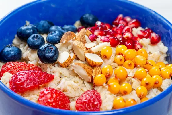 Das Konzept eines gesunden Frühstücks mit Haferbrei und frischen Beeren, Granatapfel und Mandeln close up
