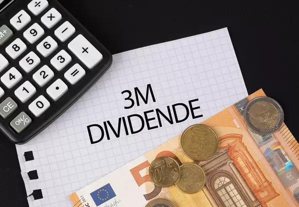 Das Konzept von 3M Dividenden: 3M Dividende Text auf einem Blatt Papier mit einigen Münzen, einem 5-Euro Schein und einem Kalkulator