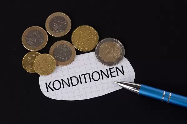 Das Konzept von Konditionen: Konditionen Text auf einem Blatt Papier mit einigen Münzen und einem blauen Stift im schwarzen Hintergrund