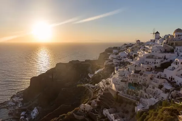 Das malerische Dorf Oia auf Santorin bei Sonnenuntergang. Die Sonne geht im Meer unter