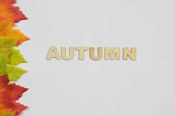 Das Wort Autumn und abgefallene Blätter