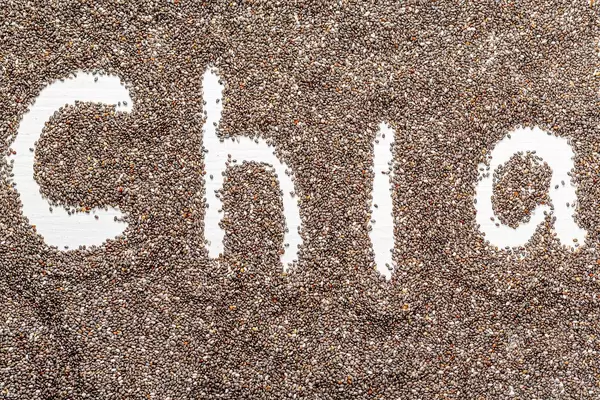 Das Wort Chia in einem Samen-Meer geschrieben, auf einem Holzuntergrund