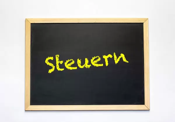 Das Wort Steuern in gelb auf einer Tafel