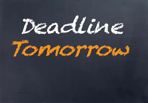 DEADLINE TOMORROW mit weißer und oranger Schrift auf schwarze Tafel geschrieben