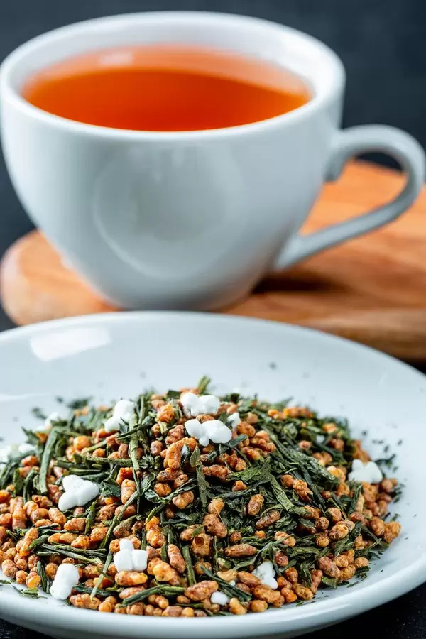 Deciduous and granulated tea with a Cup of tea behind