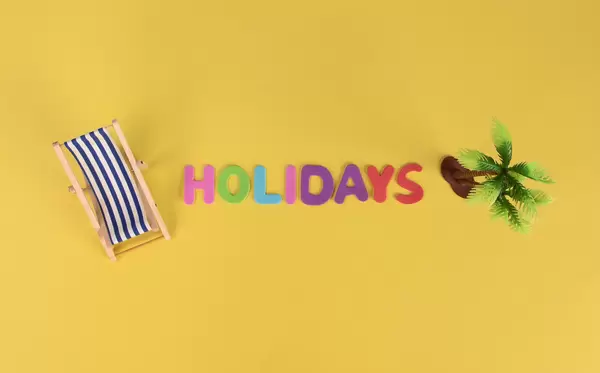 Deck chair and palm tree with Holidays text on yellow background