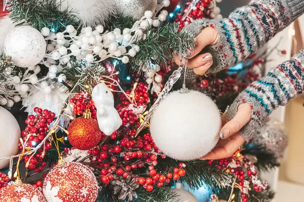 Decorated christmas tree and female hands, close-up