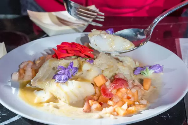 Decorated food plate: Cod fish with purple and red flowers, next to vegetables