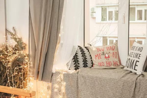 Decorated room for christmas with pillows on the windowsill and glowing garlands