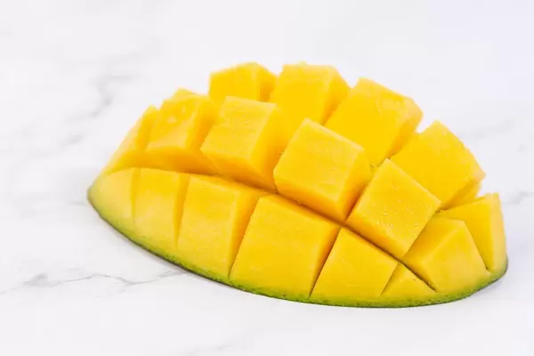 Dekorative Mango in Igelform angerichtet, auf einem weißen Marmortisch