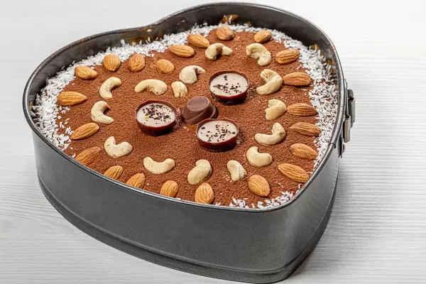 Delicious homemade chocolate cake with heart shaped nuts on white wooden background (Flip 2019)