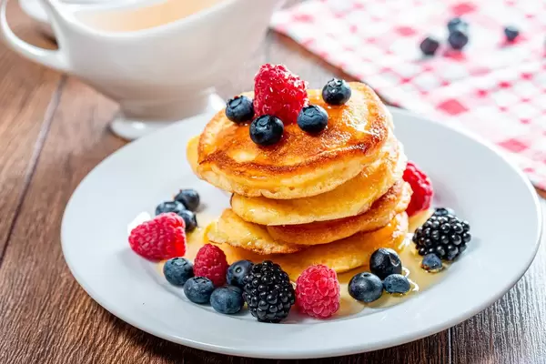 Delicious homemade golden pancakes with fresh raspberries, blueberries and mulberry (Flip 2019)