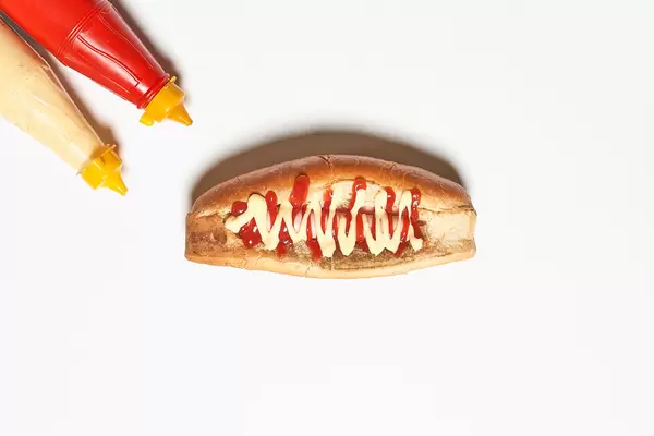 Delicious hotdog and bottles of mustard and mayonnaise