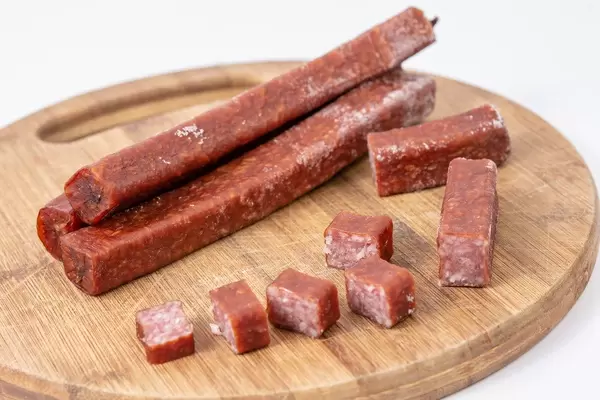 Delicious Hunting Sausage sliced and served on the wooden board (Flip 2019)
