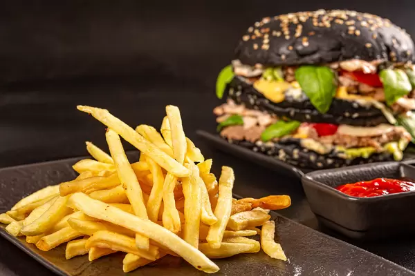 Delicious junk food background - french fries and black burger