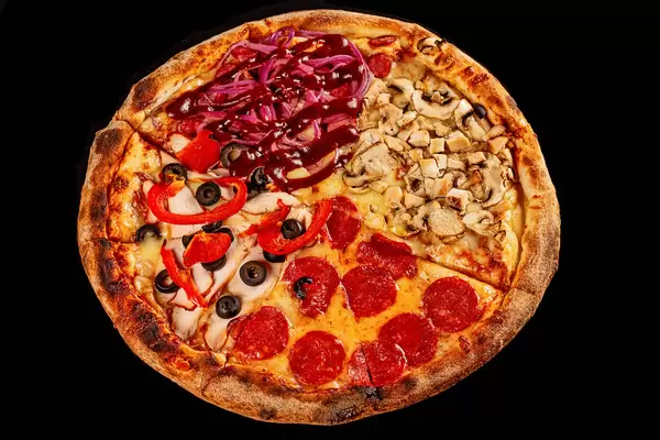 Delicious pizza with different cheeses, sausages, ham, chicken, vegetables and mushrooms