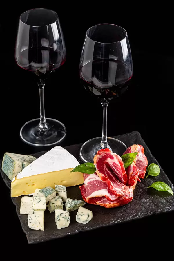 Delicious slicing of cheese and meat with red wine in glasses