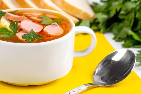 Delicious soup with carrots, onions and pieces of sausages