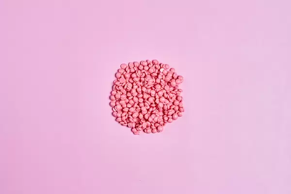 Depilatory pearly pink solid wax beans on bright colored background