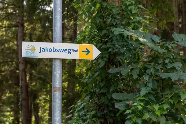 Der gelbe Pfeil des Jakobswegs nach rechts Richtung Tirol
