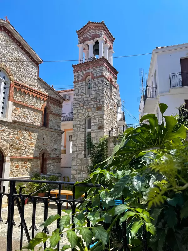 Der Glockenturm der Kirche Agios Georgios von Kyratso mit Steinmauern auf Skopelos, Griechenland
