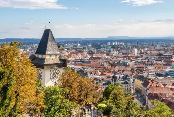 Der historische Uhrturm zwischen Bäumen in Graz, Österreich