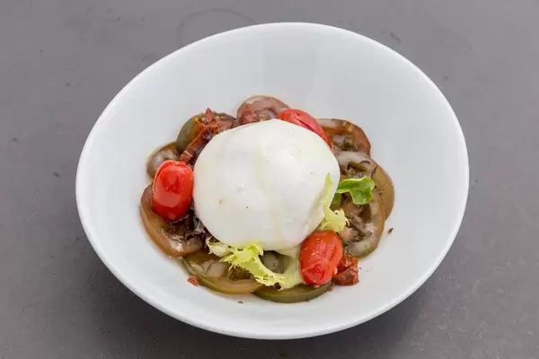 Der italienische Burrata-Käse im Salat mit Tomaten und Gurken, auf einem weißen Teller, des spanischen Restaurants Hotel 1898 in Barcelona, Spanien