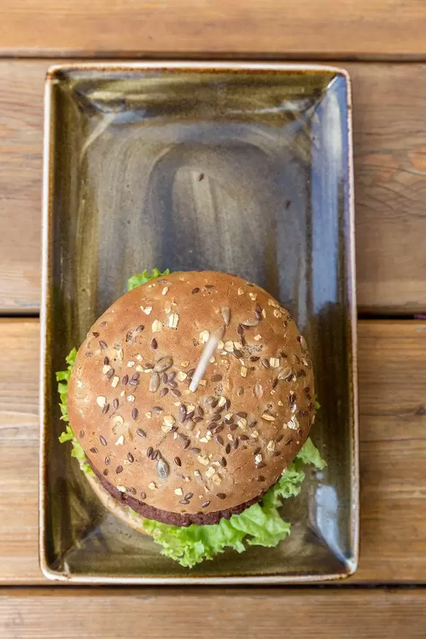 Der vegan Vitamin B 12 Burger "Naturbursche" mit Zwiebeln und Champions von Moving Mountains, auf einem Holztablett im "Hans im Glück" Restaurant