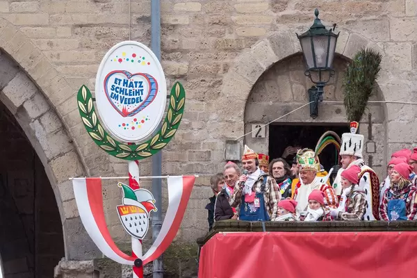 Der Zugleiter Holger Kirsch hält eine Rede mit Mikrofon an der Severinstorburg beim Rosenmontagszug