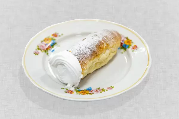 Desert-Gebäck "Süße Sahne Tube" mit Puderzucker auf Blumenteller