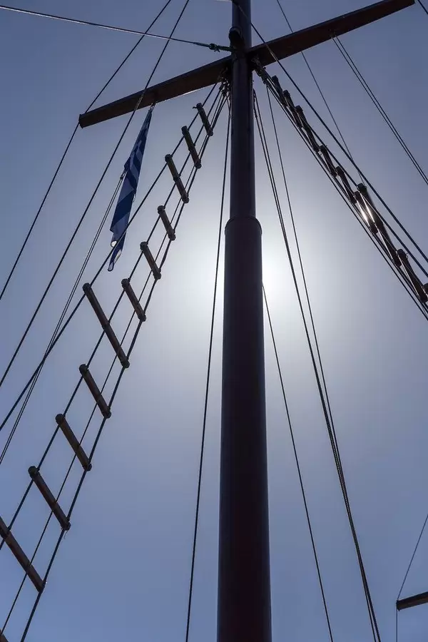 Detail eines Segelbootmasts mit griechischer Flagge von unten gesehen