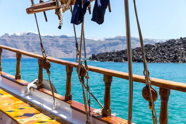 Details of a sailboat off the volcanic coast of Santorini with blue sea on a sunny day